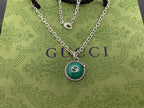 Gucci pendant necklace close-up with green medallion pendant on silver chain