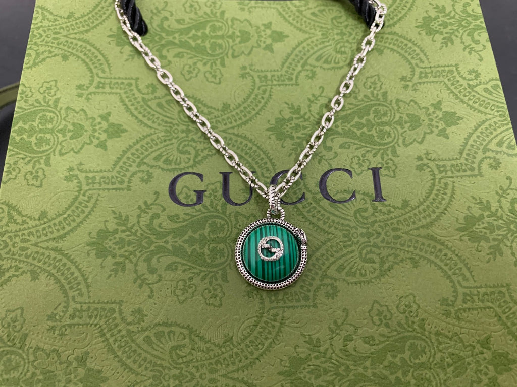 Gucci pendant necklace close-up with green round medallion and silver chain