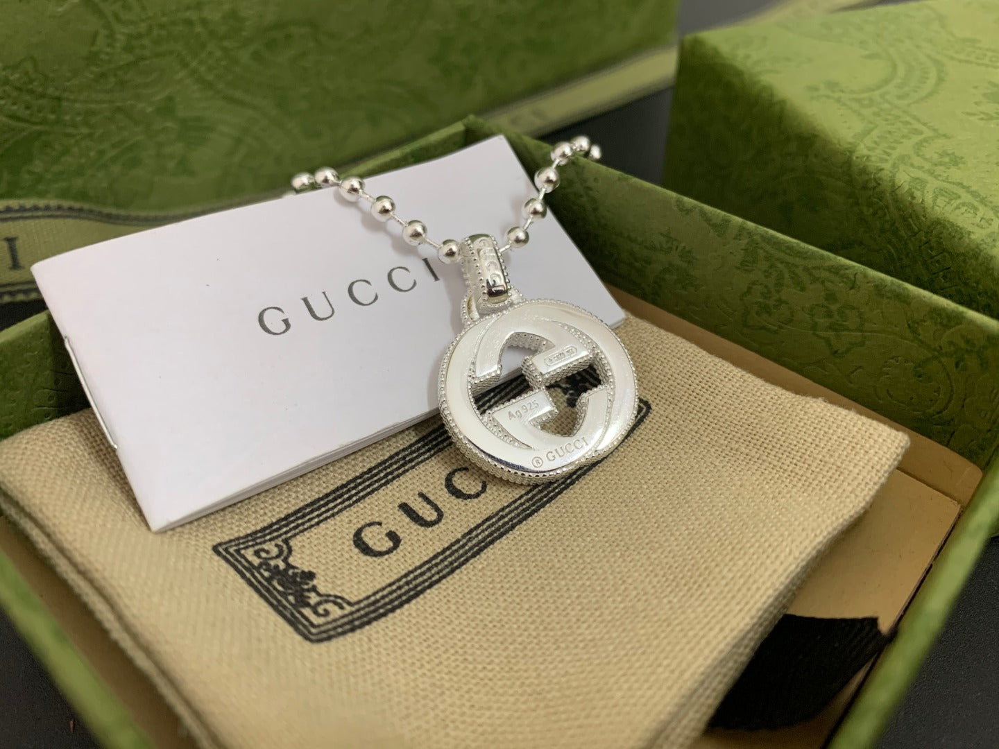 Silver-tone round interlocking G pendant necklace with beaded chain, close-up