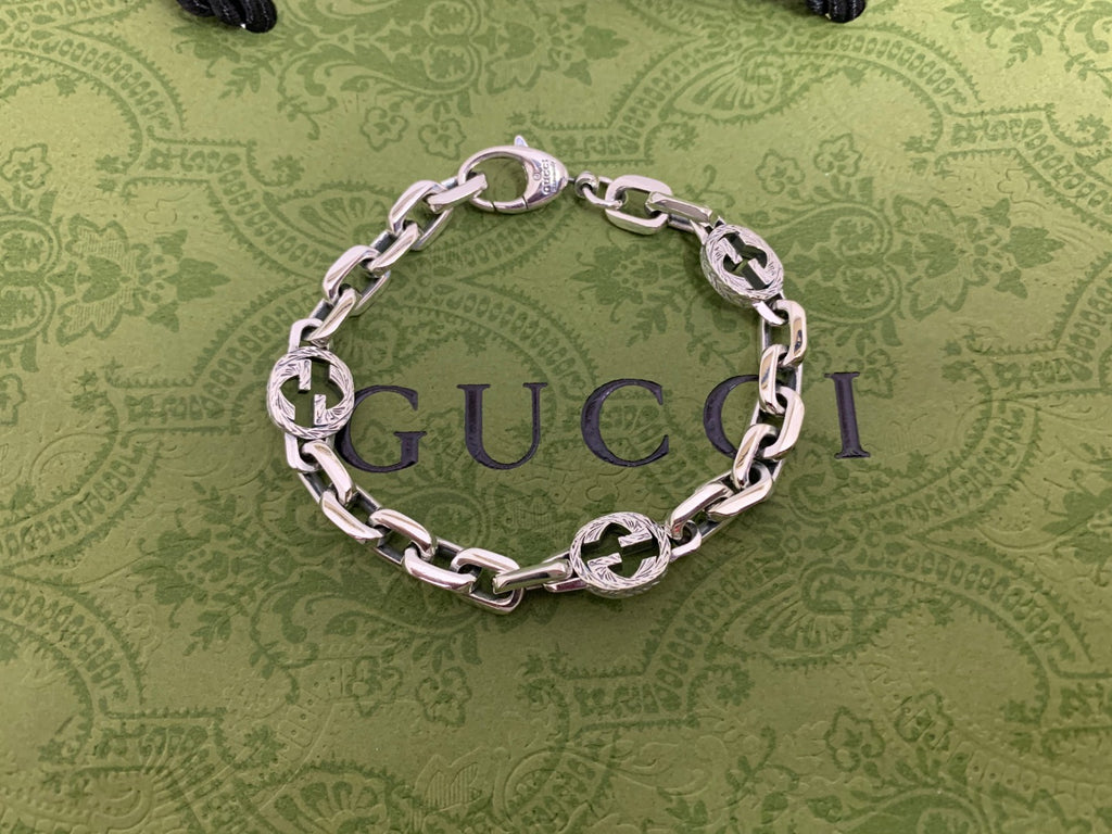 Silver-tone chain bracelet with blue enamel logo discs and silver curb links, top view