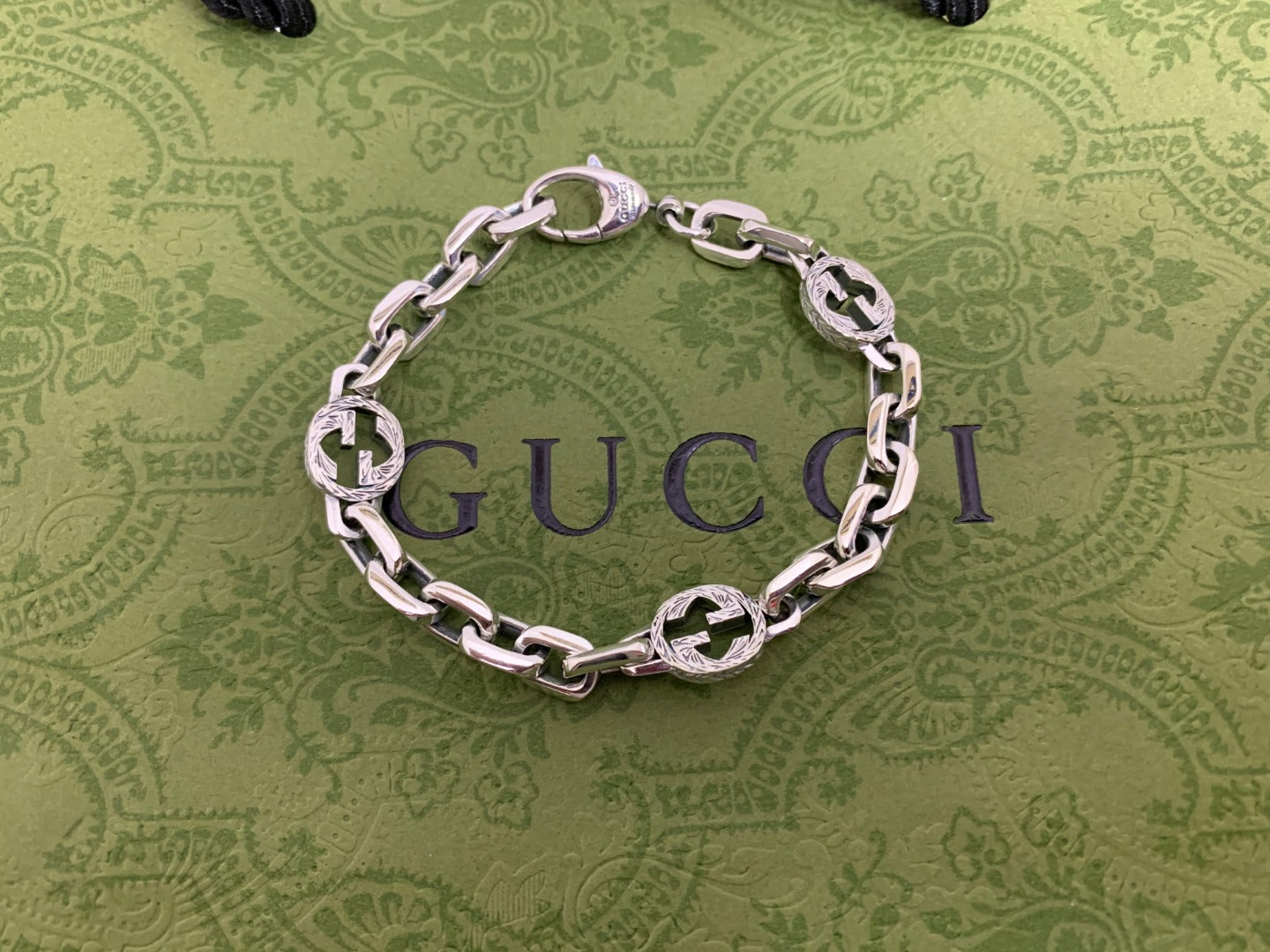 Silver-tone chain bracelet with blue enamel logo discs and silver curb links, top view