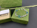 Silver-tone chain bracelet with blue enamel logo links and round clasp
