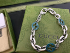 Silver-tone chain bracelet with blue enamel logo medallion links and polished curb links