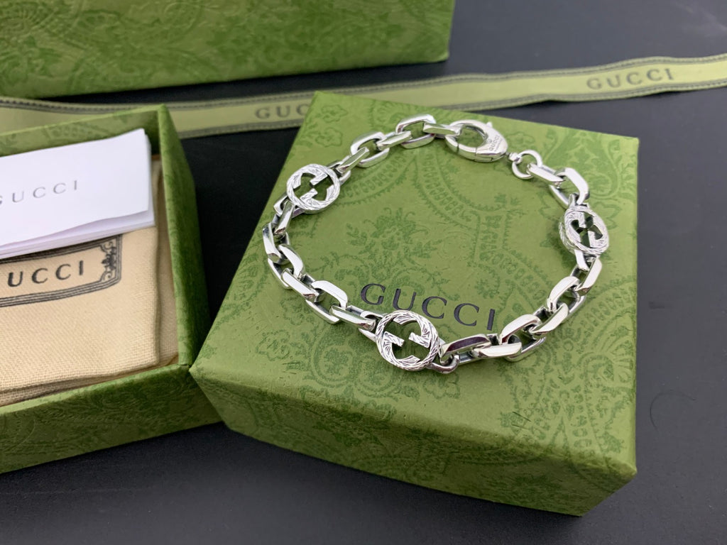 Silver-tone chain bracelet with blue enamel logo discs and round clasp, front view