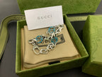 Silver-tone chain bracelet with blue enamel logo discs and round clasp, angled view