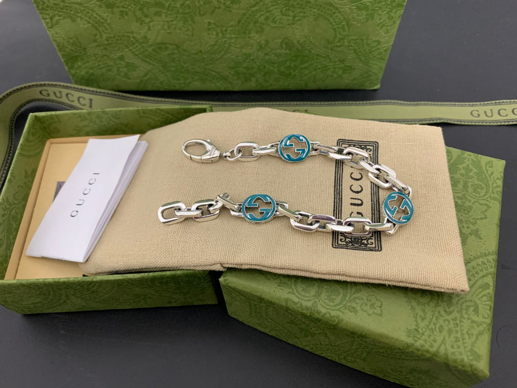 Silver-tone chain bracelet with blue enamel logo discs and rectangular logo charm