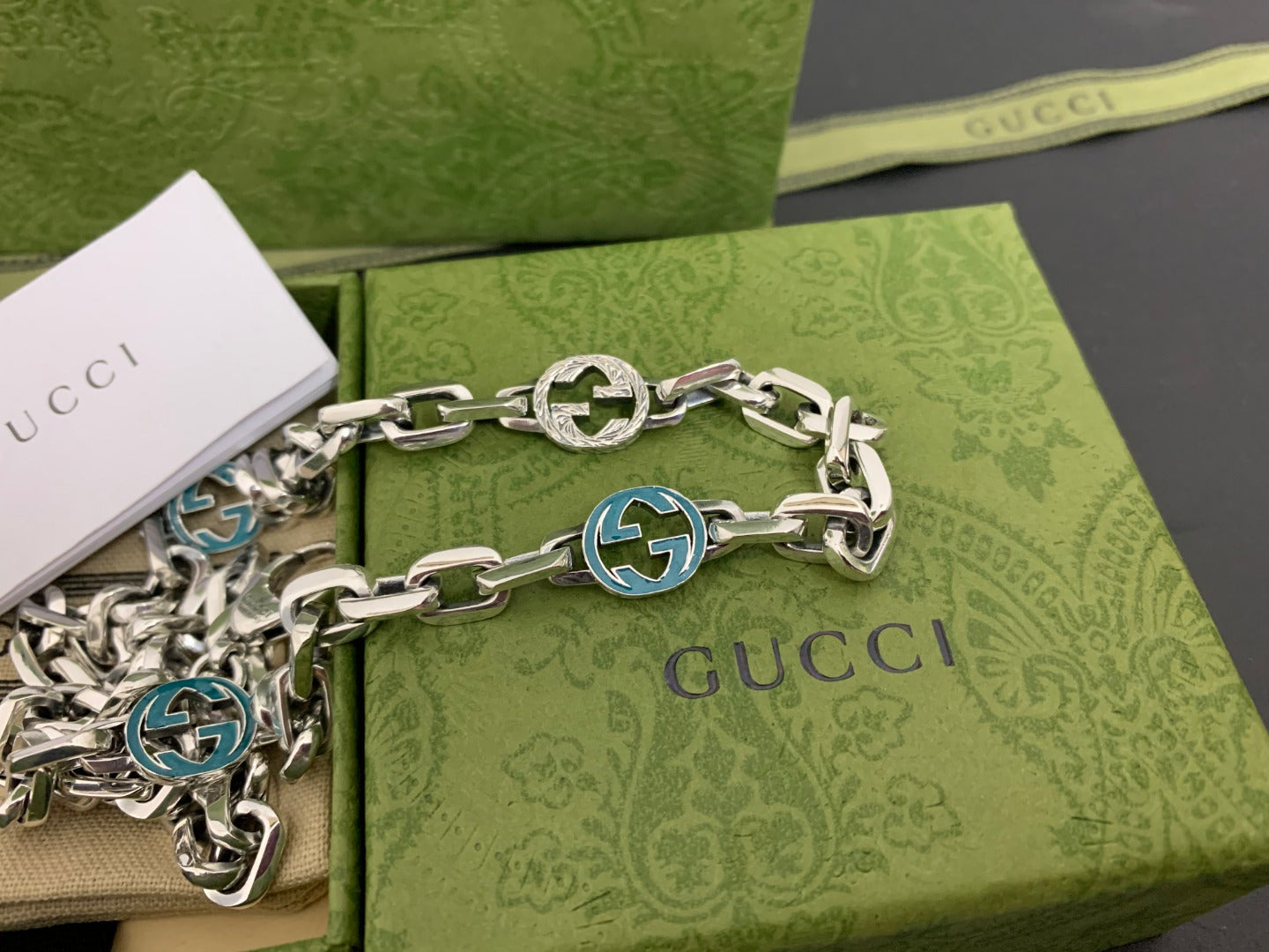 Silver chain strap with blue interlocking G medallions and clasp