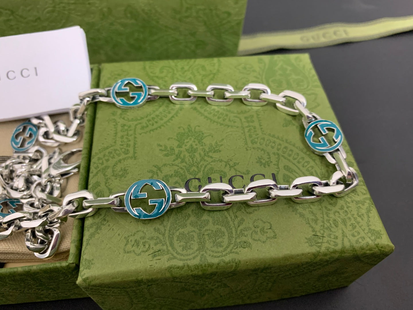 Silver chain strap with blue interlocking G medallions and clasp