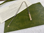 Gucci necklace with silver chain, rectangular GG pendant, and small round charm