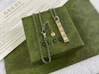 Gucci necklace with silver chain, rectangular GG pendant, and small circular tag