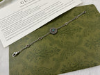Silver link bracelet with turquoise flower charm and small round logo medallions.