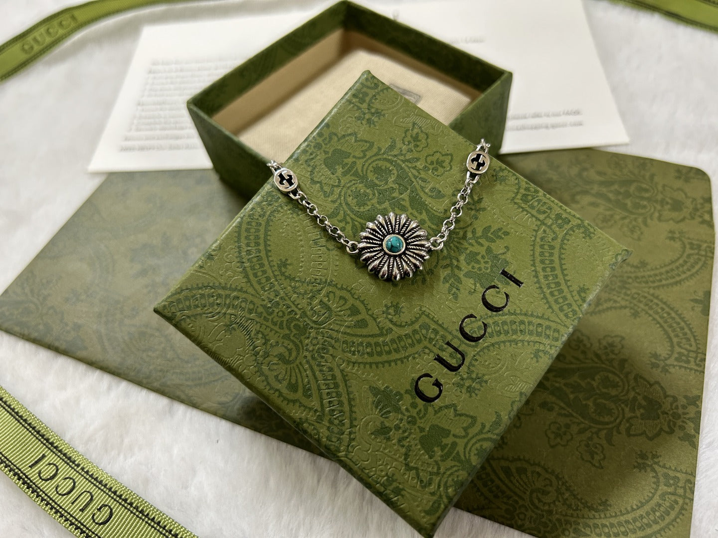 Silver charm bracelet with turquoise center flower and small logo links.