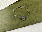 Silver charm bracelet with turquoise flower center and oval logo link pattern.