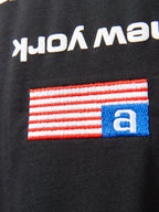 Close-up of T-shirt flag-style graphic patch with blue and red stripes and a blue letter