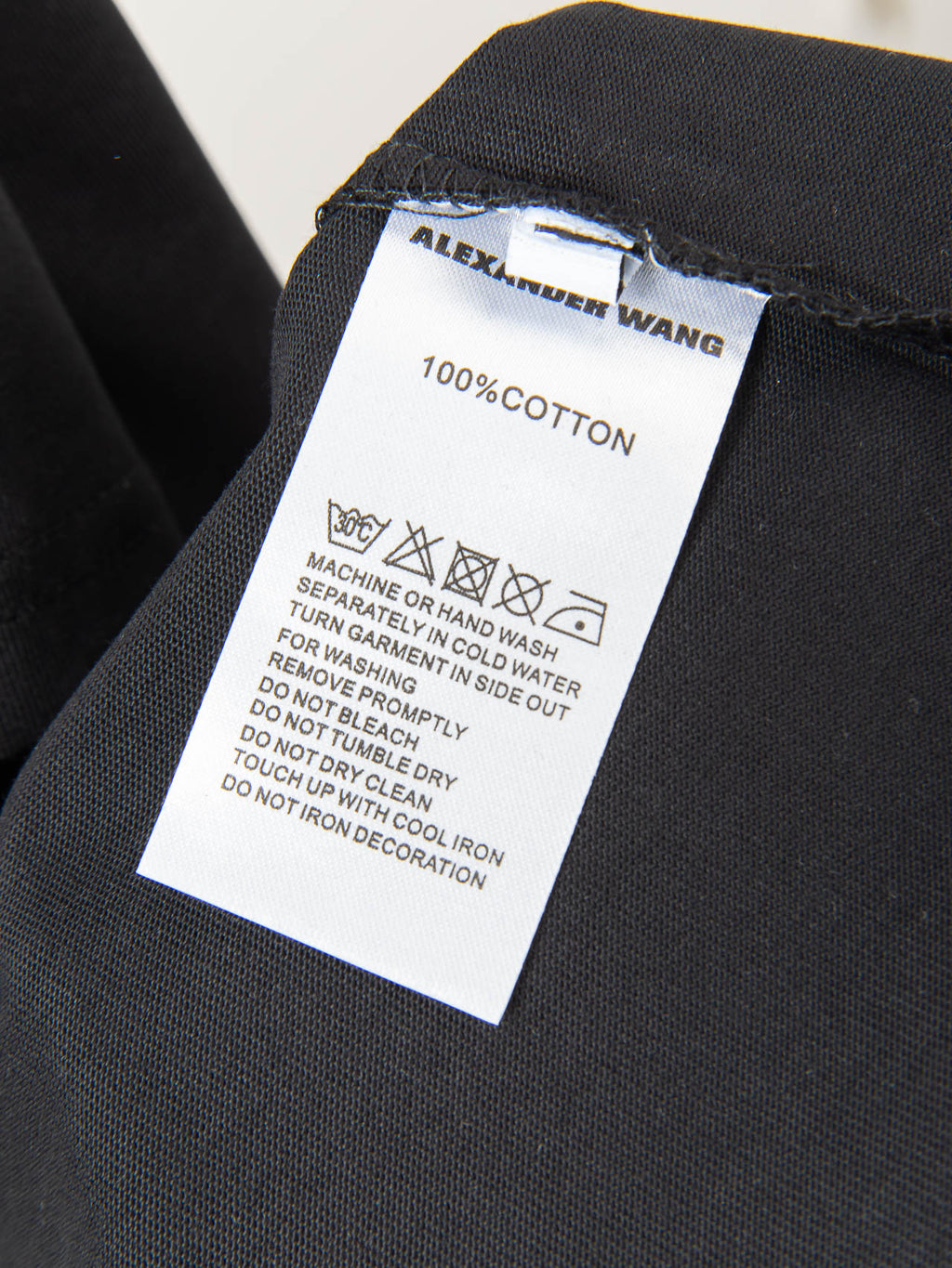 Black T-shirt care label: 100% cotton and machine wash instructions