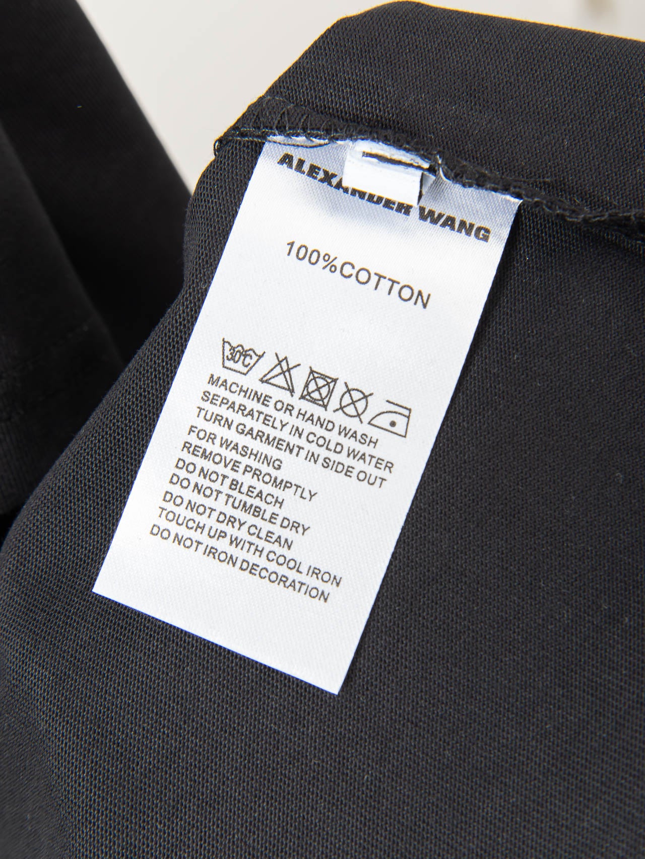 Black T-shirt care label: 100% cotton and machine wash instructions