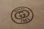 Close-up of Gucci 1971 crest logo patch on tan T-shirt