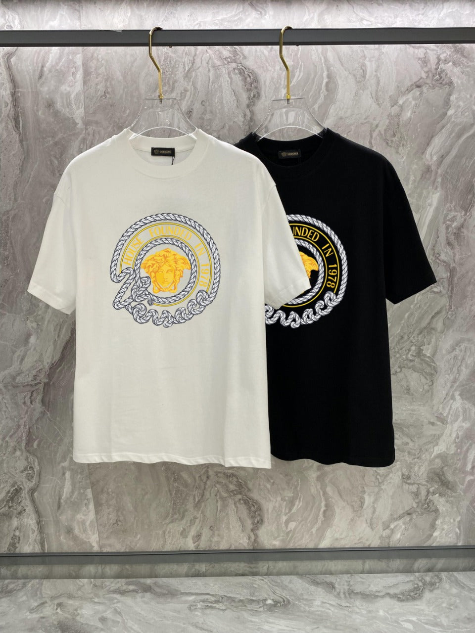 Pair of T-shirts: white and black, each with a round gold-and-blue chest graphic
