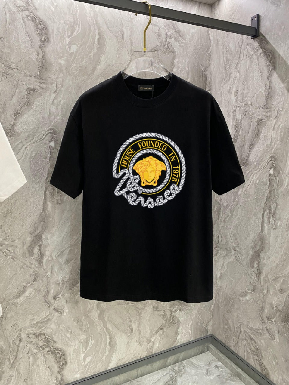 Black T-shirt with large round gold-and-white graphic on the chest