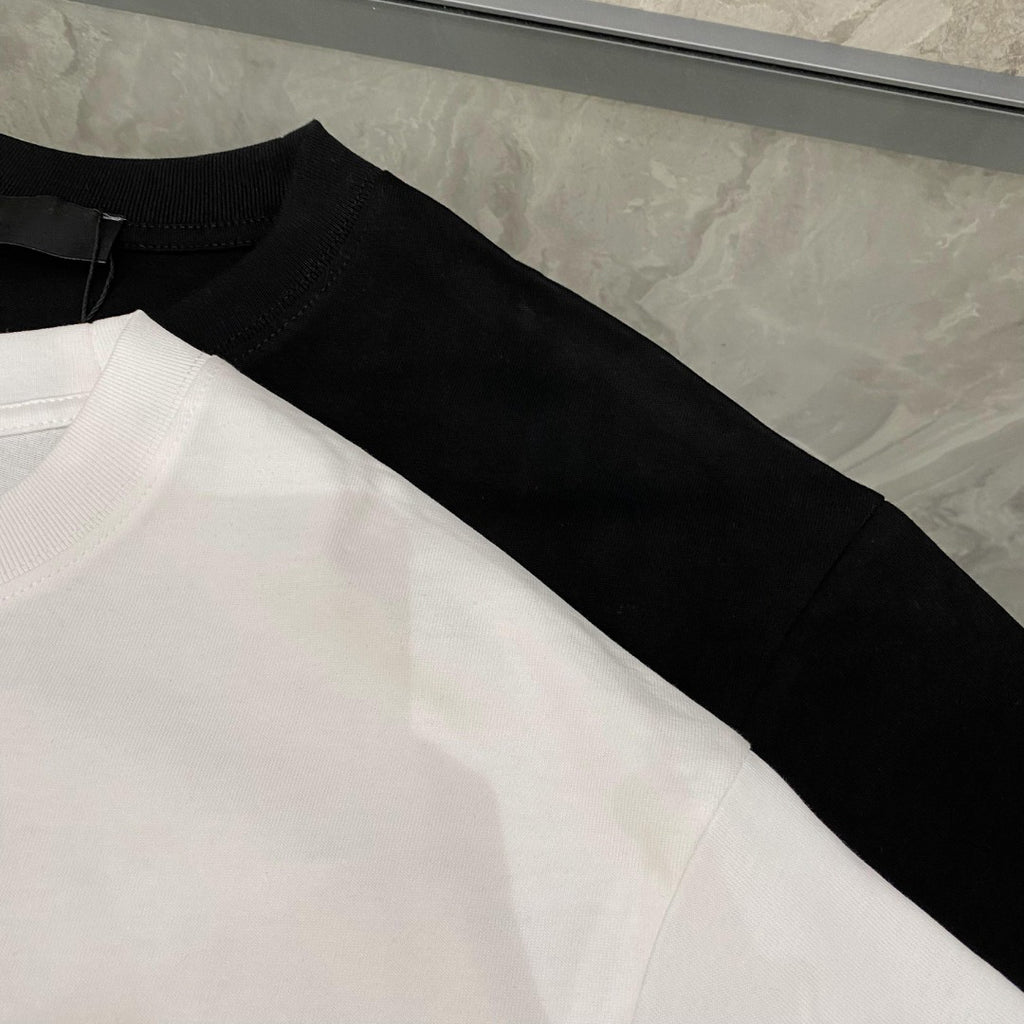 Folded T-shirts in white and black, showing short sleeves and crew necks