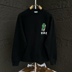 Black crewneck sweatshirt with green graphic and small DIOR logo on the chest.