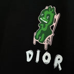 Black sweatshirt close-up of green character graphic and white DIOR logo text.