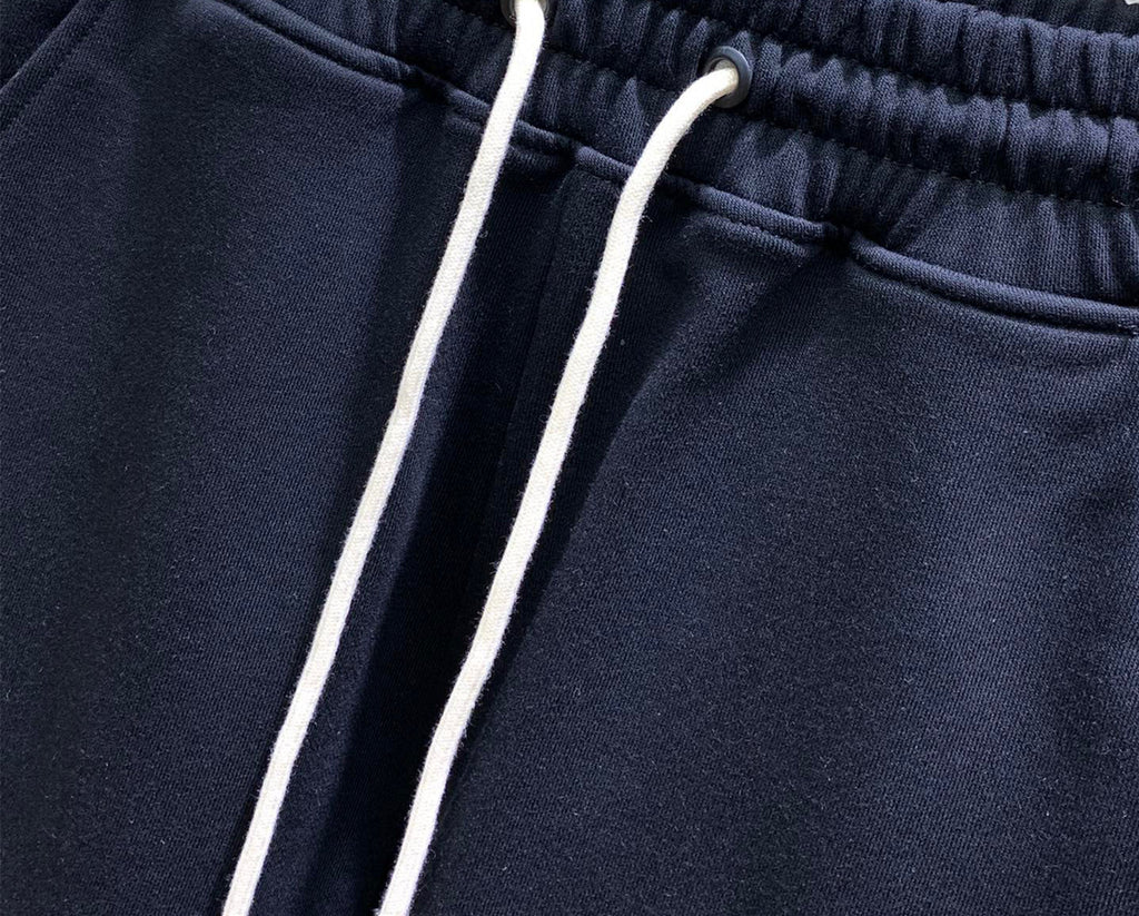 Navy drawstring track pants with two white cords and ribbed waistband