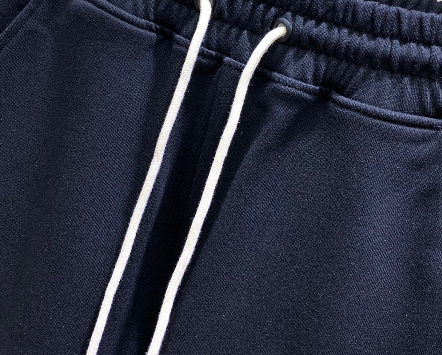 Navy drawstring track pants with two white cords and ribbed waistband
