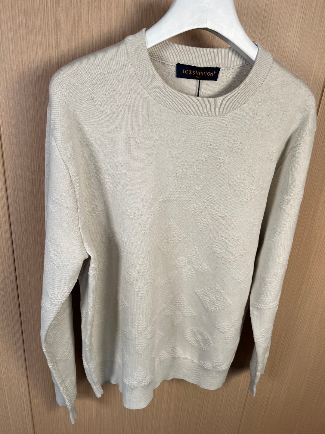 Cream crew-neck long-sleeve sweater, front view on hanger