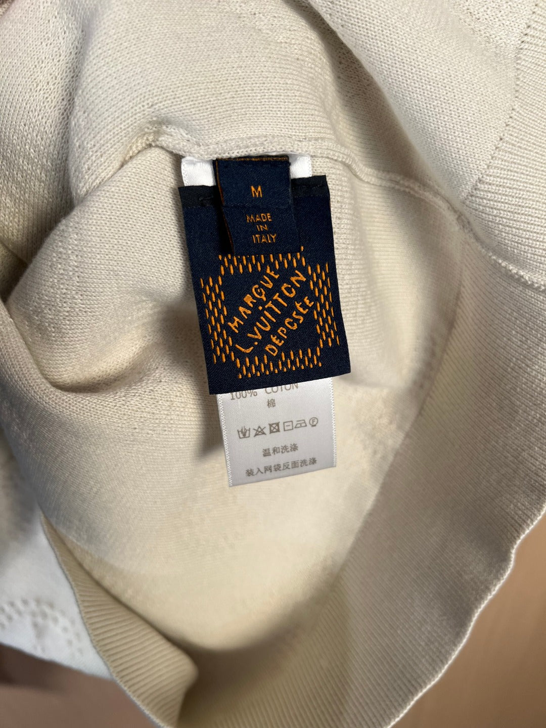 Cream sweater care label and size tag inside neckline