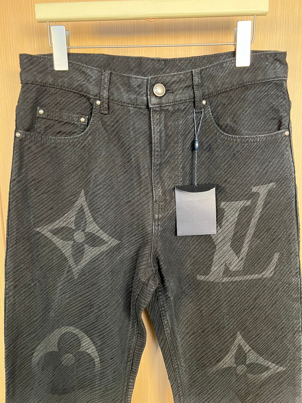 Louis Vuitton monogram jeans with front pockets and snap button hardware, close-up.