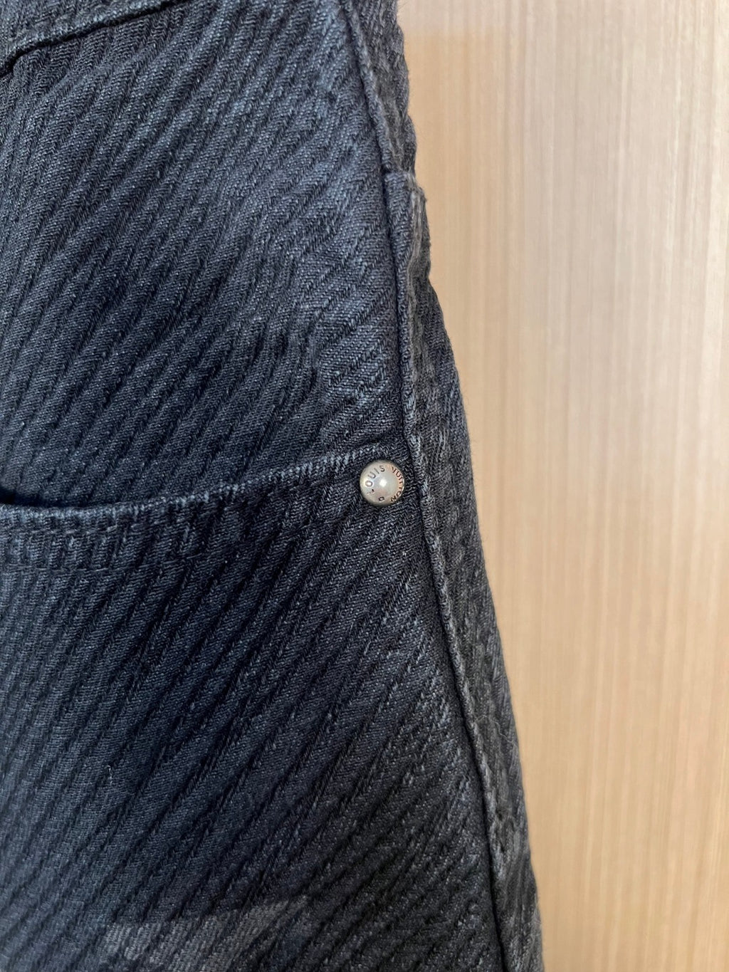 Dark denim pants with front pocket seam and small metal button detail