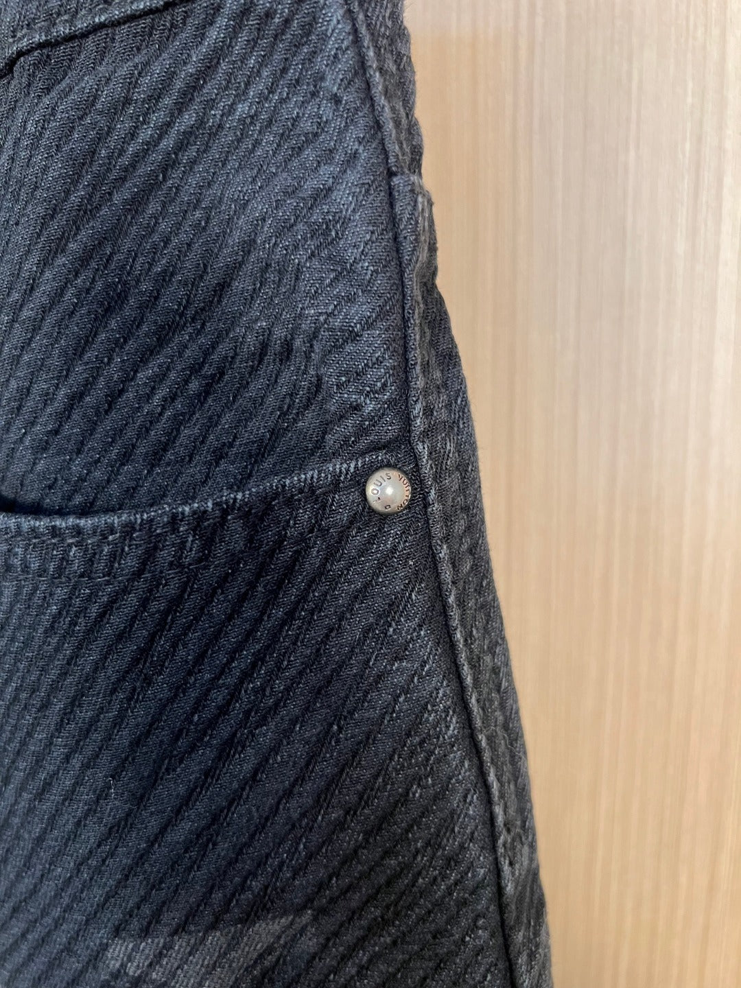 Dark denim pants with front pocket seam and small metal button detail