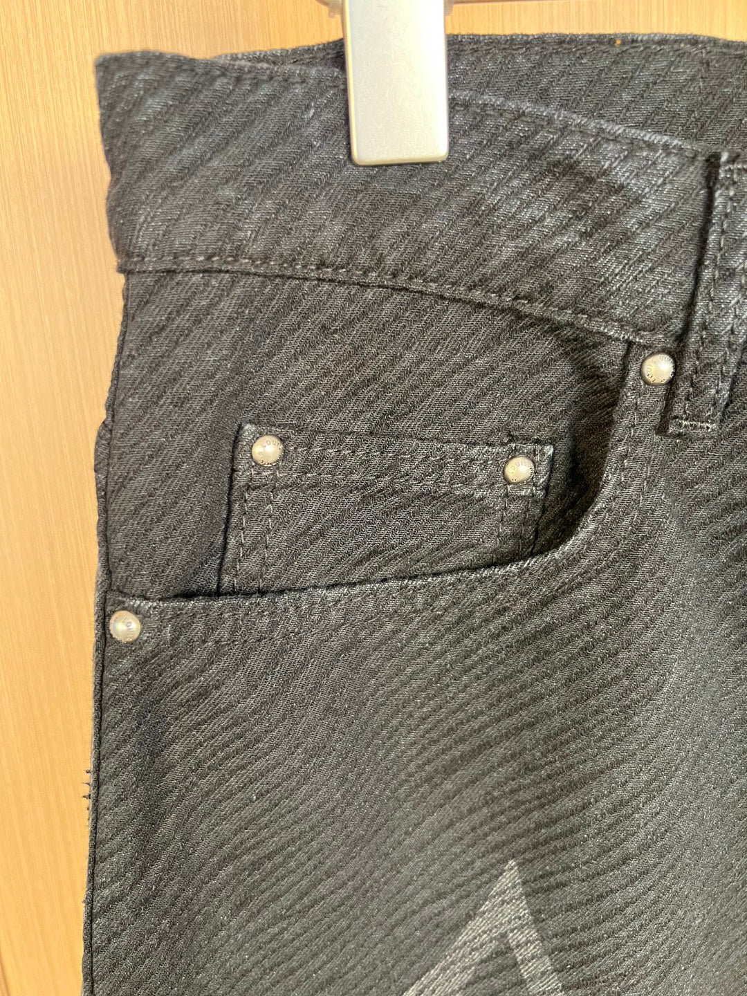 Jeans front with two inset pockets and metal rivets, close-up.