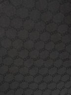 Gucci polo shirt fabric close-up, black textured interlocking pattern