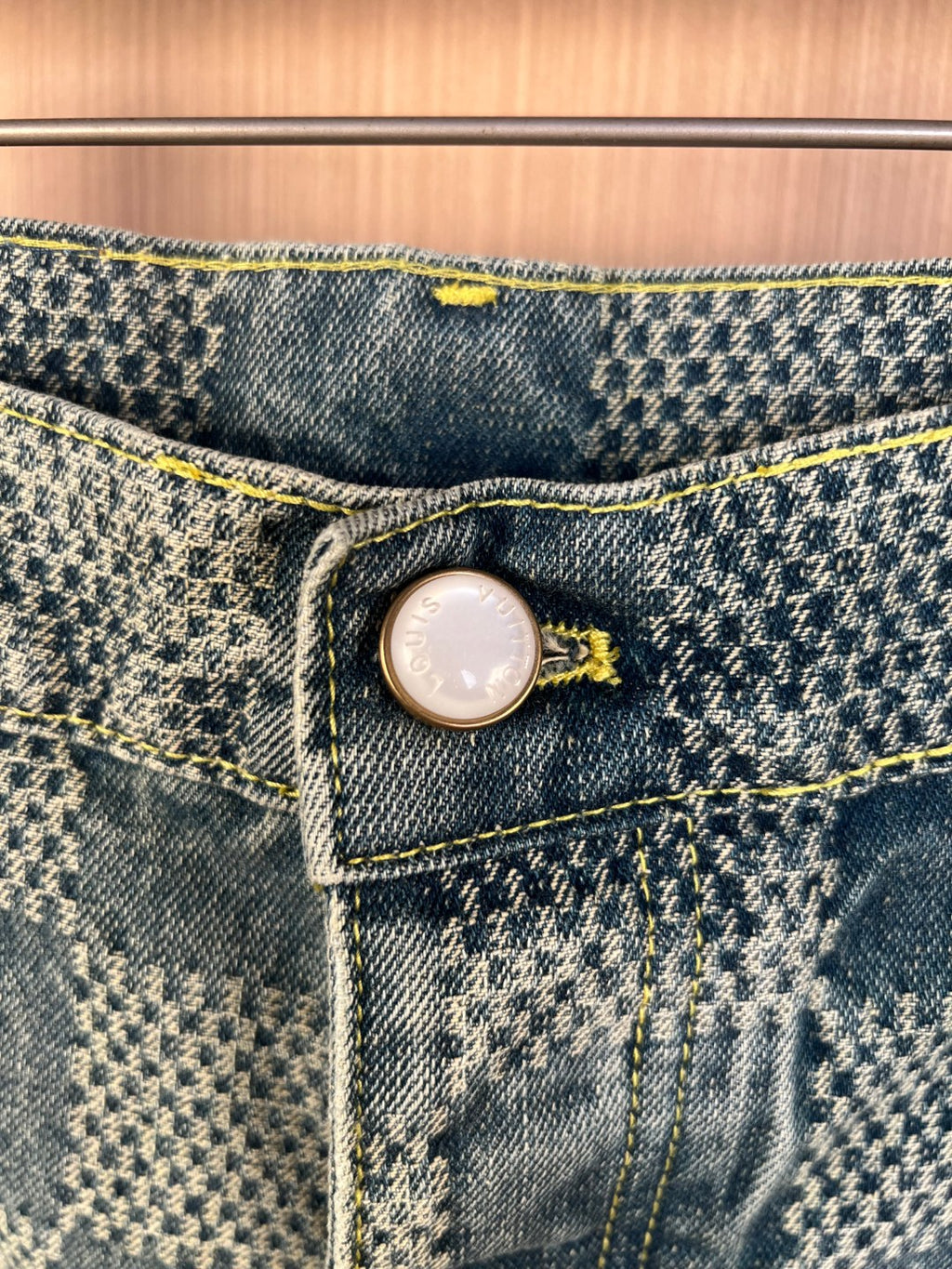 Denim shorts pants waistband with button and yellow topstitching close-up