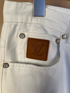 White denim pants close-up of leather logo patch and snap buttons