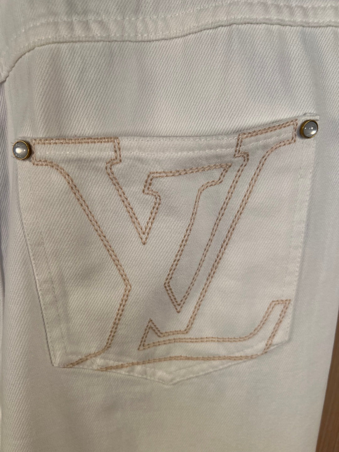 White denim pants back pocket with V-shaped embroidered emblem