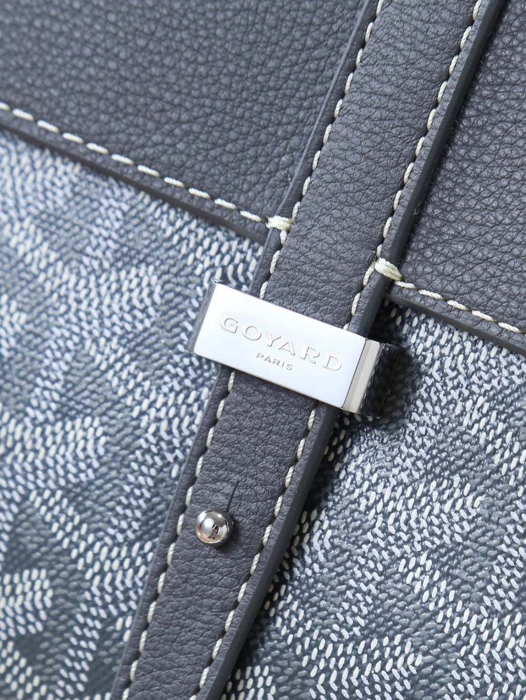Goyard shoulder bag close-up of logo tab with snap hardware on textured strap