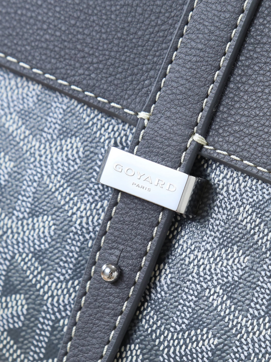 Goyard shoulder bag close-up of logo tab with snap hardware on textured strap