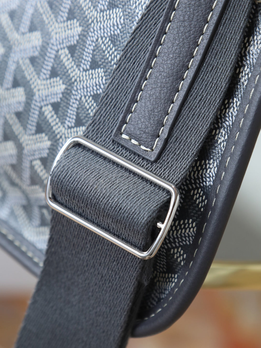 Goyard shoulder bag close-up of metal buckle and dark gray leather strap connector