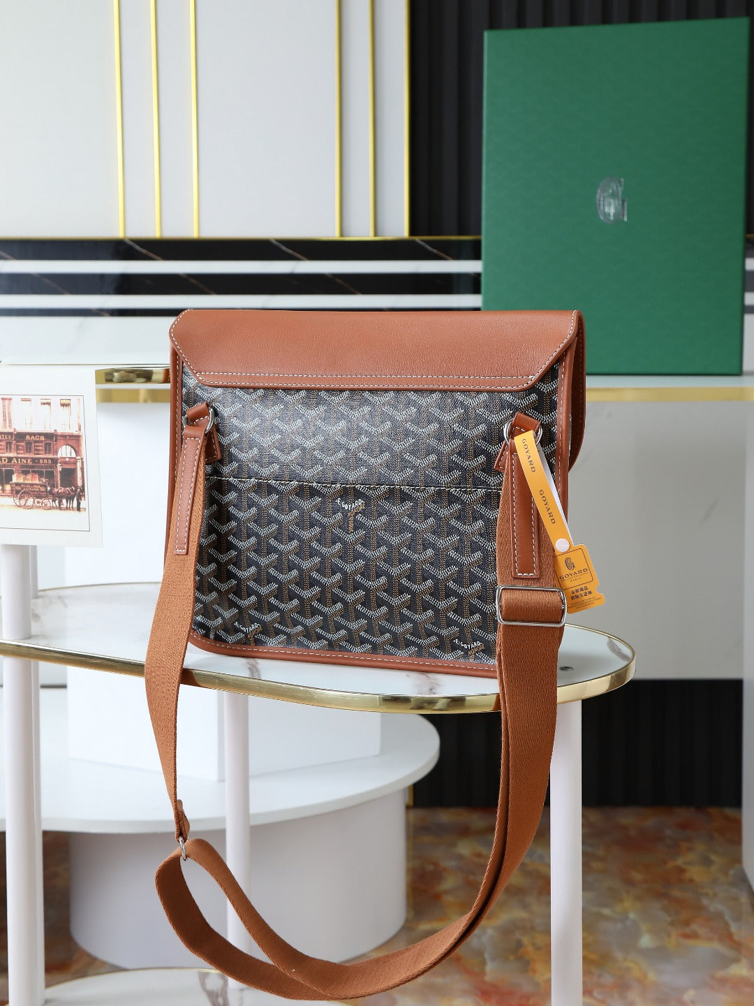 Goyard shoulder bag with monogram canvas, brown handles, and hanging yellow tag.
