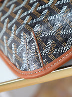 Goyard bag corner with brown leather piping and stitched monogram fabric close-up.
