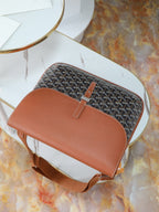 Goyard bag top view with brown leather flap, gray monogram canvas, and short strap.