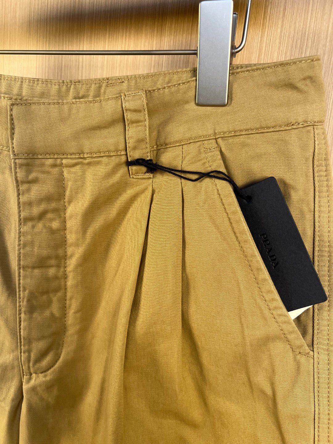 Khaki Prada shorts with button closure, belt loops, and black string detail