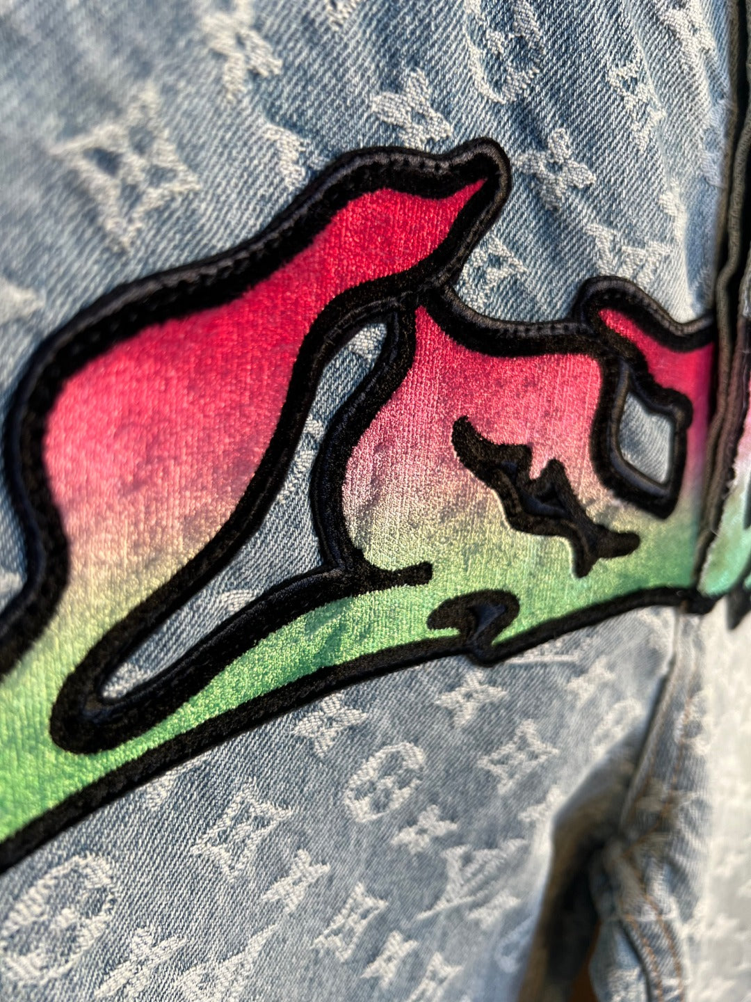 Colorful graffiti patch on light blue monogram denim pants leg