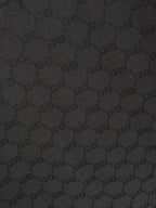 Black Gucci polo shirt fabric close-up showing repeating GG monogram pattern