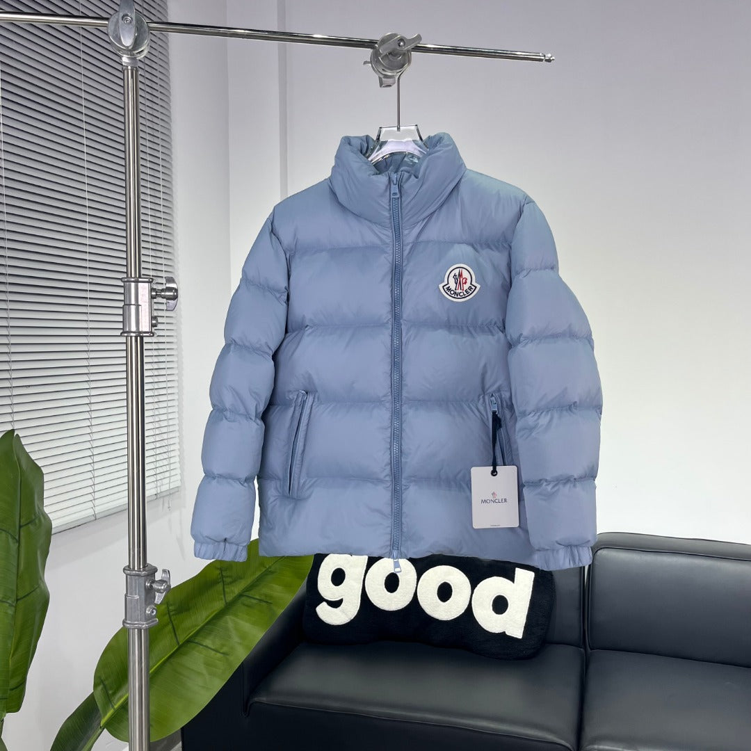 Light blue Moncler puffer jacket with full zip, hood, and chest logo patch
