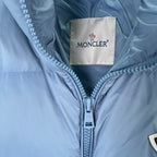 Moncler label at collar of light blue puffer jacket with front zipper