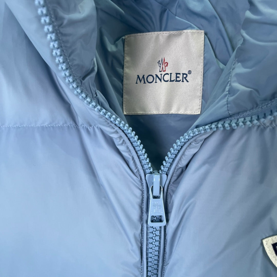 Moncler label at collar of light blue puffer jacket with front zipper
